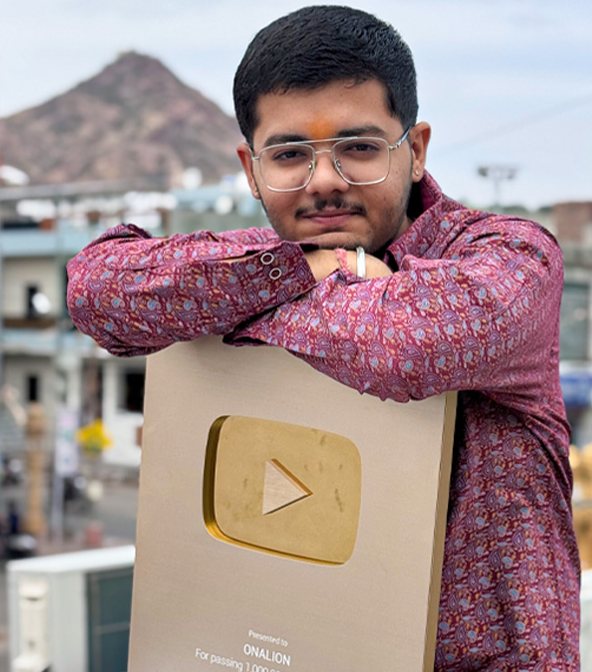Tarjan Khatri leaning on a YouTube Gold Play Button engraved with the channel name Onalion, smiling at the camera