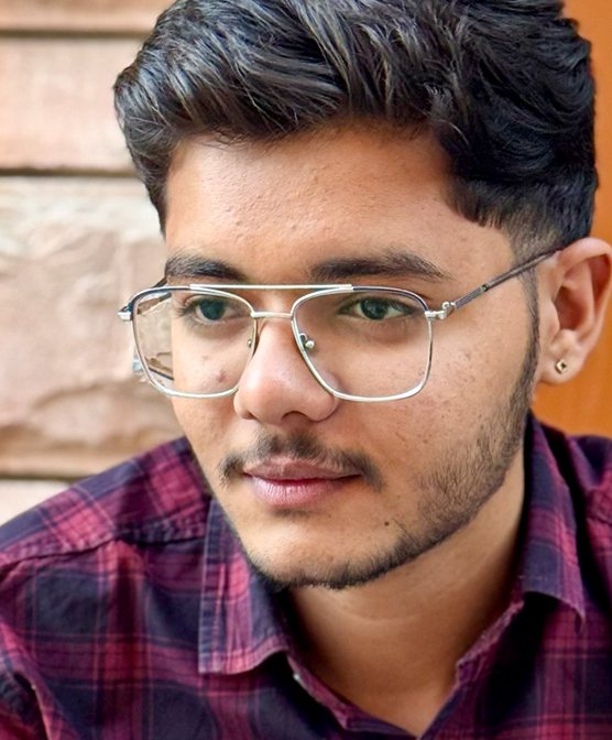 Close-up portrait of Tarjan Khatri wearing metal-frame glasses and a checked shirt