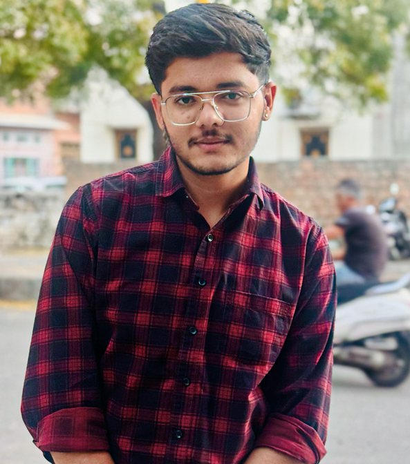 Tarjan Khatri in a red checked shirt and glasses, standing on a street